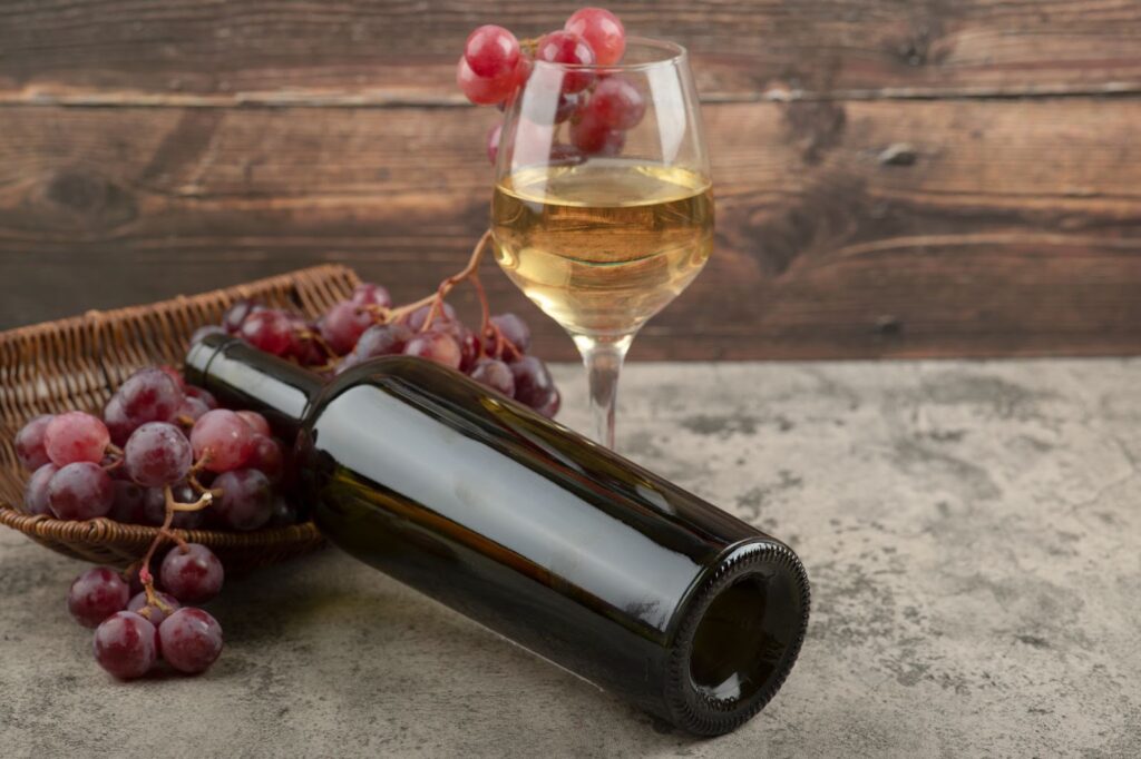 A bottle of red wine and a glass of white wine on a wooden table.