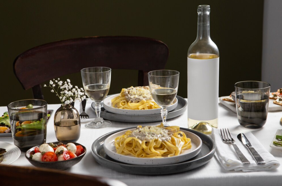 Elegant dinner table set with pasta and white wine